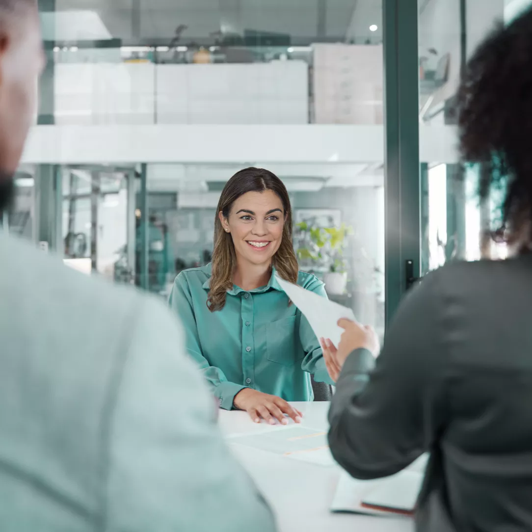 Drei Personen sitzen sich in einem Büro aus Glas gegenüber